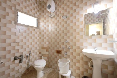 a bathroom with a sink and a toilet and a mirror at Hotel Hospice in Surat