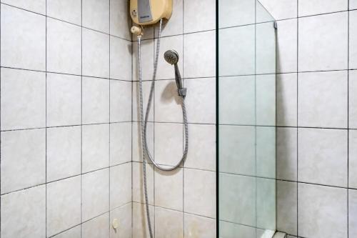 a shower with a shower head on a tiled wall at Super OYO 91366 The Chatter Place in Bandung