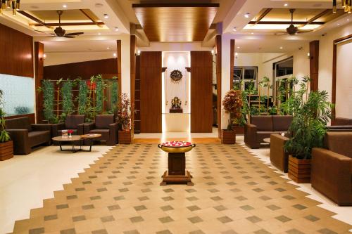 a lobby with couches and tables and plants at 7 Apple Resort, Lonavala in Lonavala
