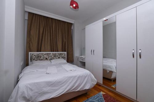 a bedroom with a white bed and a bathroom at Doğal apart in Trabzon