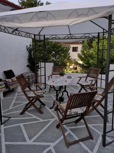 a patio with a table and chairs under a white umbrella at Zeta's house Argalasti in Argalasti