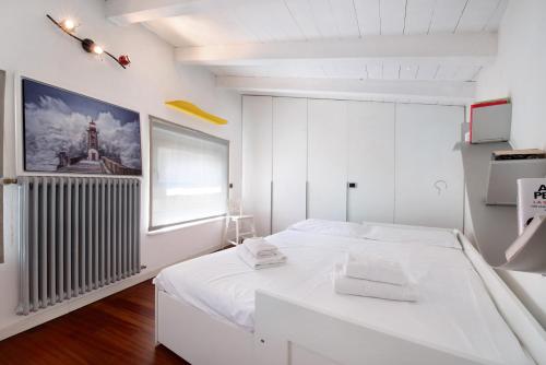 a white bedroom with a white bed and a window at Penthouse in Città Alta - Bergamo in Bergamo