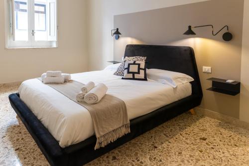 a bedroom with a black bed with towels on it at Casa Franca in Marsala