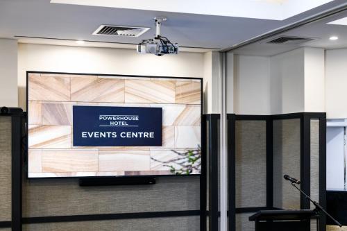 a screen in a room with a sign on the wall at Powerhouse Hotel Tamworth by Rydges in Tamworth