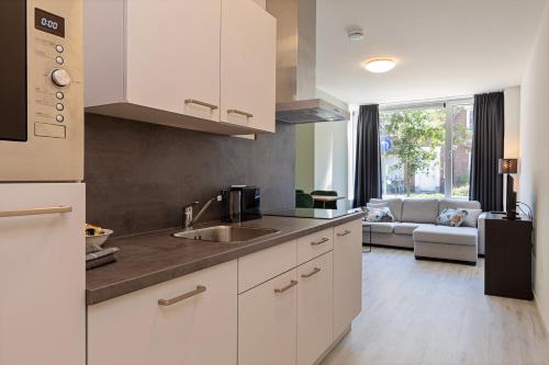 a kitchen with a sink and a living room at Eindhoven City Suites Hertogstraat F Modern 4P in Eindhoven