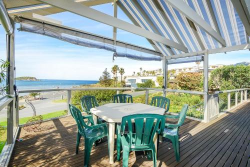 a table and chairs on a deck with a view of the ocean at Magnificent Views Over the Bay in Encounter Bay