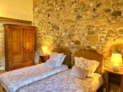 a bedroom with two beds and a stone wall at LE CLOS D'ALET in Alet-les-Bains