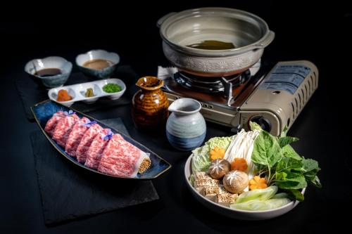 a table with two plates of food and a grill at Onsen at Moncham in Mae Rim