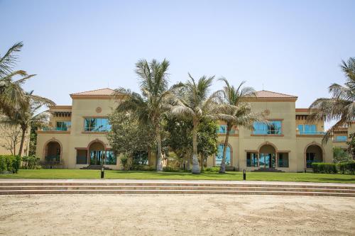 a building with palm trees in front of it at Al Raha Beach Resort & Spa in Abu Dhabi