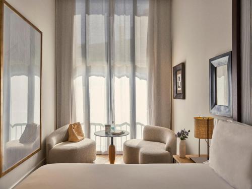 a bedroom with a bed and two chairs and a window at Hotel Pulitzer Barcelona in Barcelona