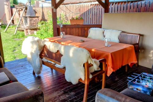 a table with a large white dog sitting at it at Lend apartman in the garden in Miercurea-Ciuc
