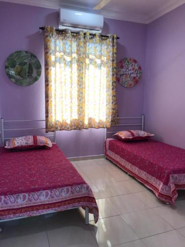 two beds in a room with purple walls and a window at D'Pantai Homestay Kuala Sg. Baru in Malacca