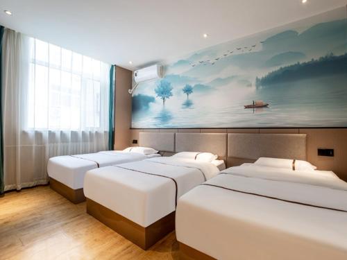 three beds in a room with a painting on the wall at Thank Inn Plus Cangzhou Weiming Road Huabei Commercial Building in Cangzhou