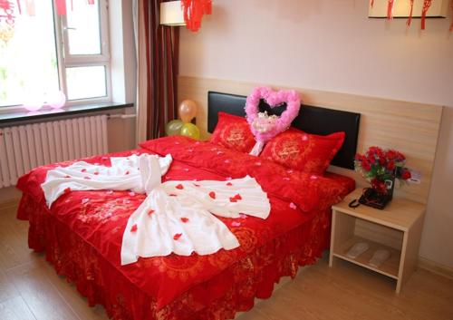 ein Schlafzimmer mit einem Bett mit einer roten Tagesdecke und einem Valentinstag in der Unterkunft Thank Inn Chain Hotel Heilongjiang qiqihar Longsha District Middle Hospital High-Speed Railway South Station in Qiqihar