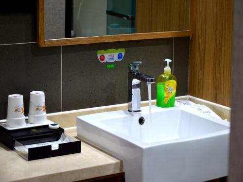 een wastafel in de badkamer met een fles zeep en een spiegel bij Up And In Shanxi Taiyuan University of Finance and Economics South Campus in Taiyuan