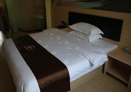 1 cama grande con sábanas y almohadas blancas en Thank Inn Chain Hotel Heilongjiang qiqihar Longsha District Middle Hospital High-Speed Railway South Station, en Qiqihar