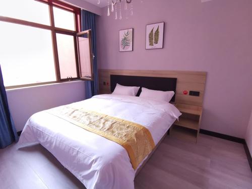 1 dormitorio con 1 cama grande con sábanas blancas en JUN Hotels Shanxi Yuncheng Yongji Bus Station, en Yuncheng
