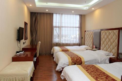 a hotel room with three beds and a window at JUNYI Hotel Hebei Zhangjiakou West Bridge District Ciershan Street in Zhangjiakou