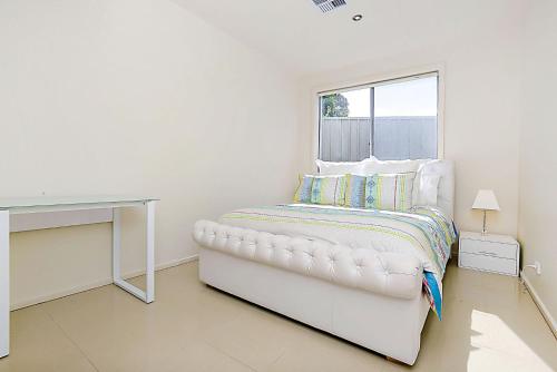 a white bedroom with a white desk and a bed at Luxury and Beachfront on Franklin in Encounter Bay