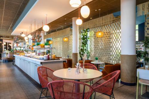 a restaurant with red chairs and tables and a counter at ibis Paris Coeur d'Orly Airport in Orly