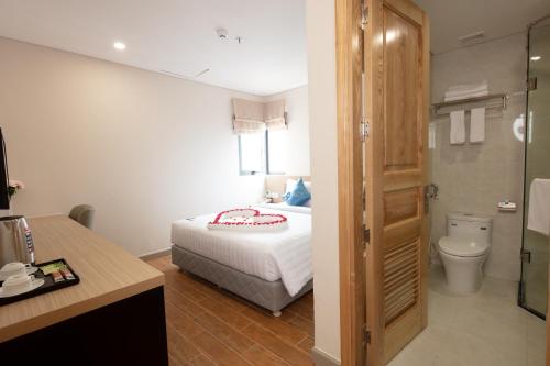 a bedroom with a bed and a bathroom with a toilet at Elite Hotel Nha Trang in Nha Trang