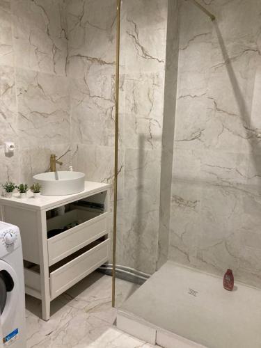 y baño blanco con lavabo y ducha. en Cosy appartement in Paris, en París