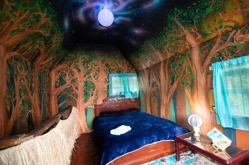 Un dormitorio con una habitación temática de árboles con una cama en Cabaña Azulado vista a Laguna en Pasto