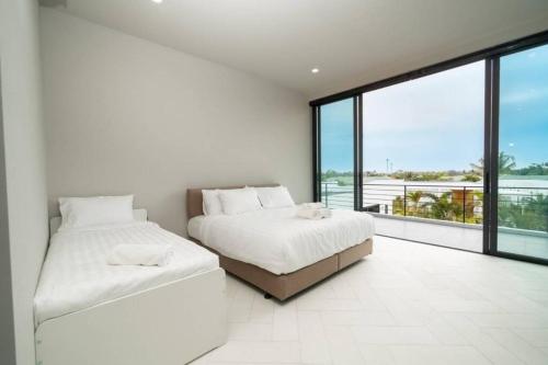 a white bedroom with two beds and a large window at The Stay Huahin 2 in Khao Tao