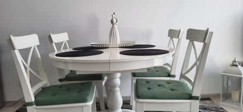 a white table with two green chairs around it at Apartament Przejazdowa in Racibórz