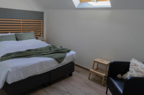 a bedroom with a bed and a chair at Au Petit Canteleu - Bed & Breakfast in Beloeil