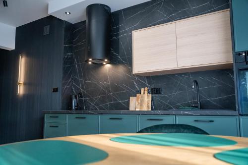a kitchen with blue cabinets and a wooden table at Lake Rental Spacerowa in Mikołajki
