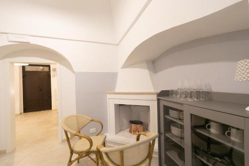 a living room with a fireplace and two chairs at Trullo Alfieri - Relax e Garden in Alberobello