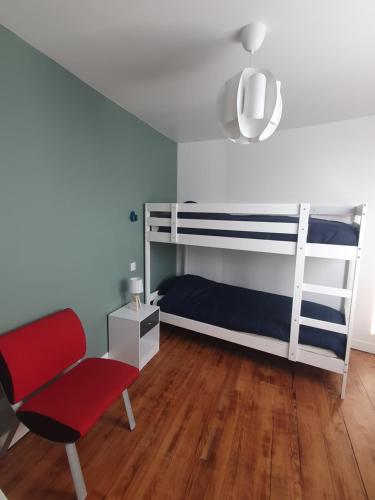 una camera con letto a castello e sedia rossa di Appartement cosy a Lourdes