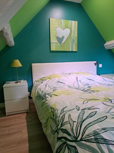 - une chambre avec un lit et un mur vert dans l'établissement La maison des animaux de compagnie, à Grumesnil