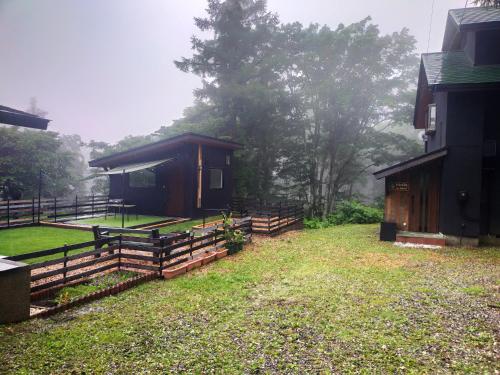 a cabin with a fence next to a house at HIEDA SANSO in Otari
