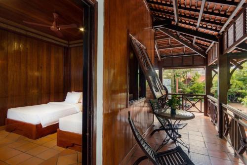 a room with a bed and a balcony with a bed and chairs at NeakBong Residence in Siem Reap