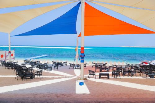 Triumph White Sands Hotel في مرسى مطروح: مجموعة من الكراسي ومظلة على الشاطئ