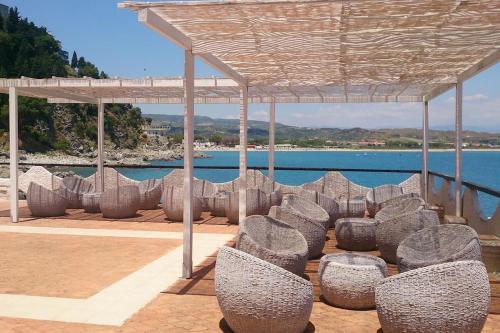 a group of chairs sitting under a pavilion near the water at Trilocale IMMinens mari in Copanello