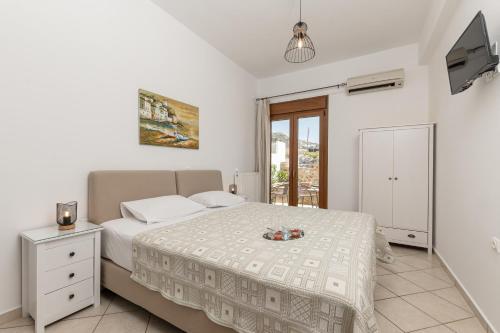 een witte slaapkamer met een bed en een televisie bij Vaso studios & apartment in Naxos town in Naxos Chora