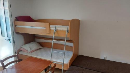 a bunk bed in a room with a table at Ana apartman in Bar