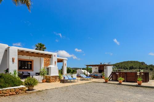 a house with a patio with chairs and a table at Villa Cana Clara in Sant Carles de Peralta