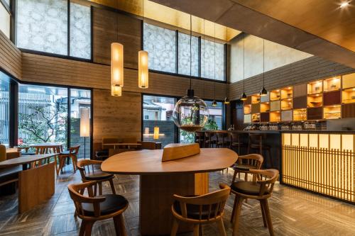 un restaurante con mesa de madera y sillas en Genji Kyoto, a Member of Design Hotels, en Giommachi