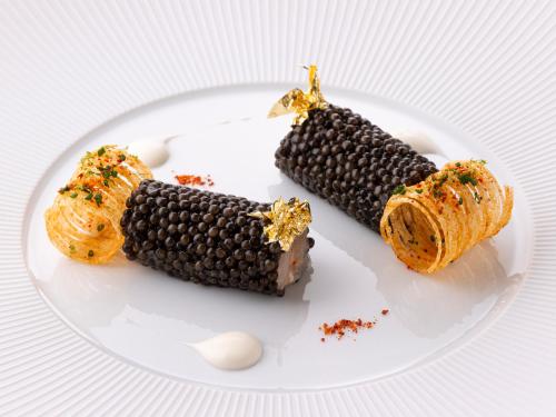 une assiette de nourriture avec du maïs noir sur le pavé dans l'établissement Hôtel Métropole Monte-Carlo - Deux restaurants étoilés, à Monte-Carlo