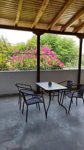 une terrasse avec une table, des chaises et des fleurs roses dans l'établissement Deluxe Studio Tolo, à Tolón