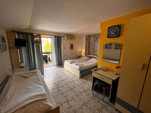 a hotel room with a bedroom with a desk and a bed at Kъща за гости Христина in Lozenets