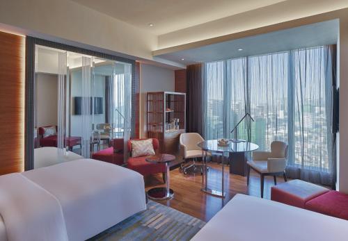 ein Hotelzimmer mit einem Bett und einem Wohnzimmer in der Unterkunft Grand Hyatt Manila in Manila