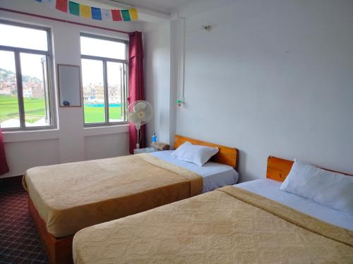 um quarto de hotel com duas camas e duas janelas em COMMUNITY HOLIDAY INN em Panaoti