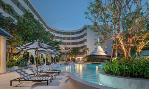 a pool with chairs and umbrellas and a building at The Royal Paradise Hotel & Spa - SHA Extra Plus in Patong Beach