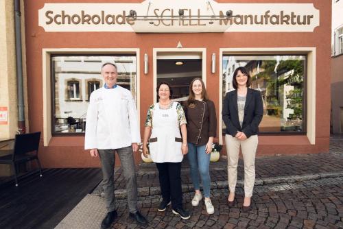 un grupo de personas de pie en frente de una tienda en Schell Schokoladen, en Gundelsheim
