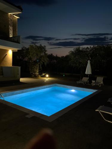 a swimming pool in a backyard at night at Olea Luxury Villa in Skala Rachoniou
